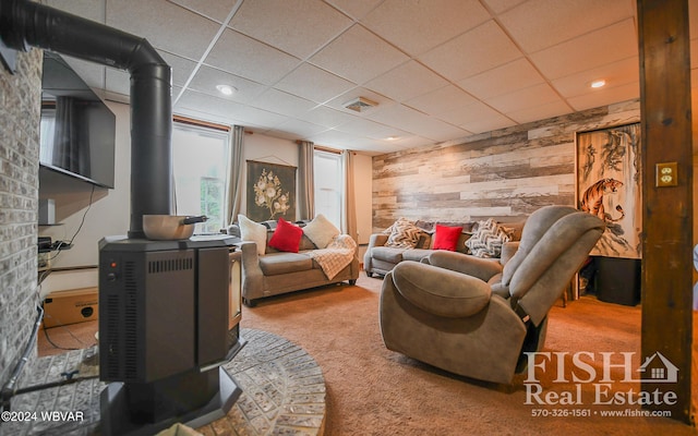 living room with carpet flooring, a wood stove, and wood walls