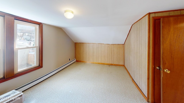 additional living space featuring lofted ceiling, a baseboard radiator, and wood walls