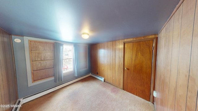 carpeted spare room with baseboard heating and wood walls