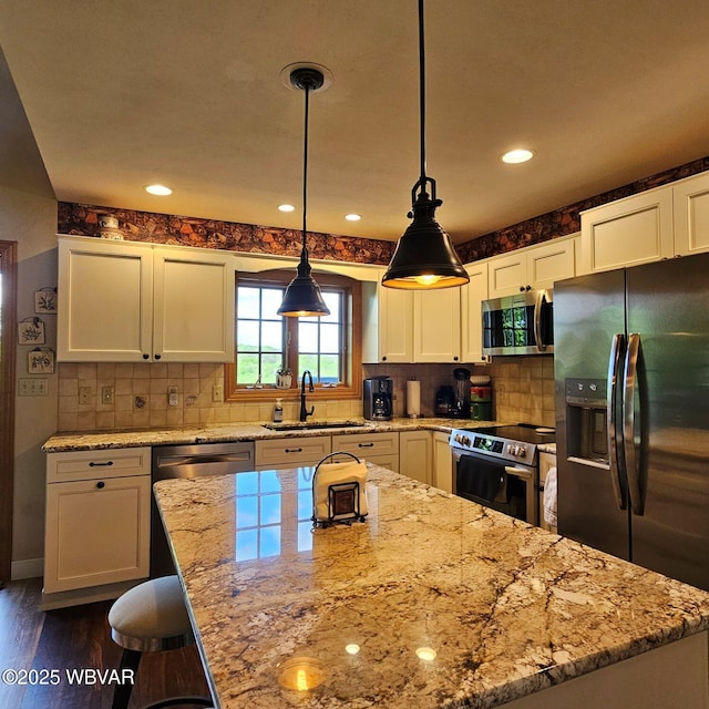 kitchen with appliances with stainless steel finishes, a sink, light stone counters, white cabinetry, and recessed lighting