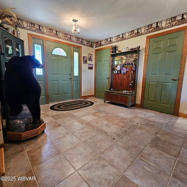 tiled foyer entrance with a chandelier and baseboards