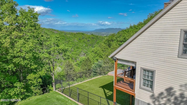 view of yard with a wooded view and a wooden deck