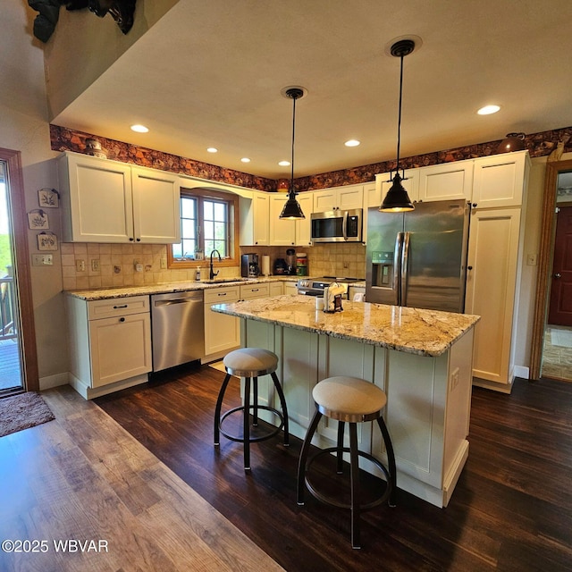 kitchen with stainless steel appliances, a sink, dark wood-style flooring, white cabinets, and recessed lighting