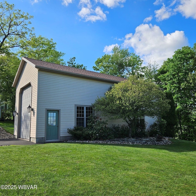 view of property exterior featuring a lawn, driveway, and an outbuilding