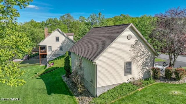 view of side of property with a yard, a chimney, and a wooden deck