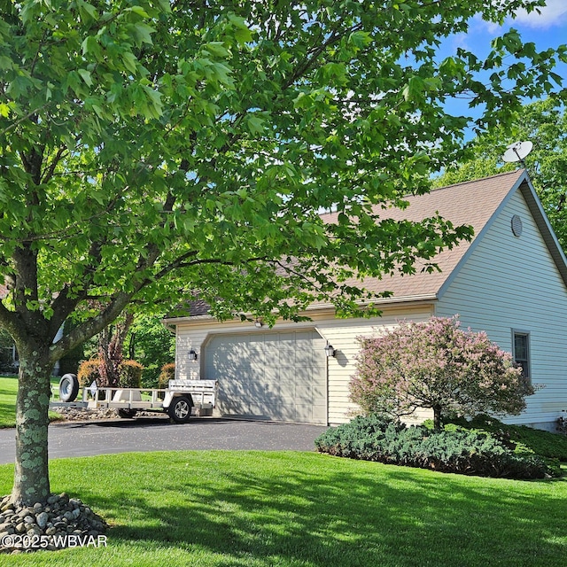 view of home's exterior featuring a lawn, an attached garage, and a shingled roof