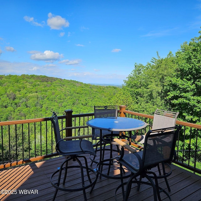 wooden deck featuring a forest view and outdoor dining area