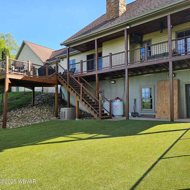 back of property featuring a yard, a chimney, stairway, and a deck
