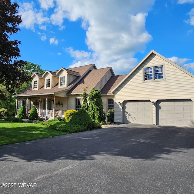 view of front of house featuring driveway, a front lawn, and covered porch