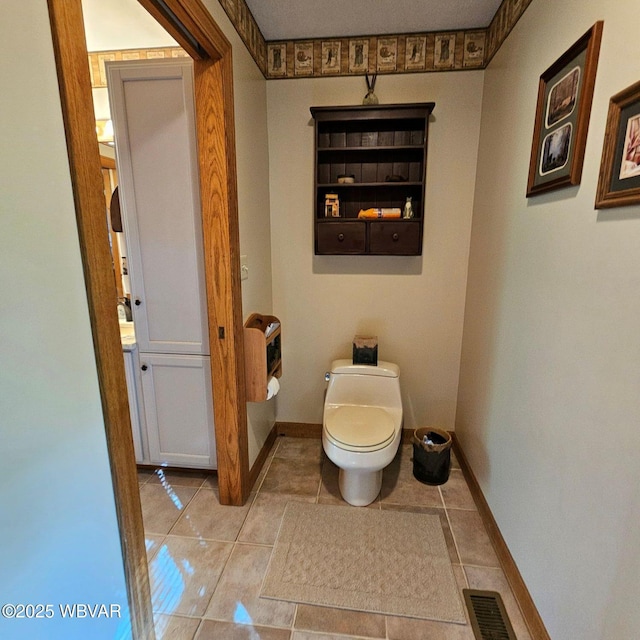 bathroom featuring toilet, tile patterned floors, heating unit, and baseboards
