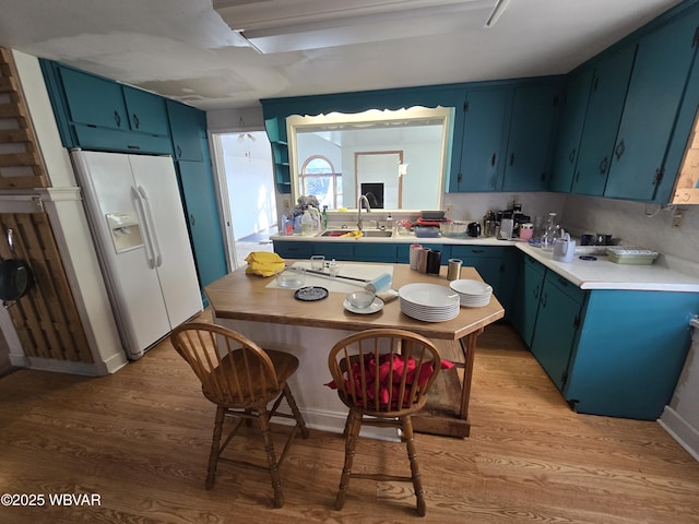 kitchen featuring blue cabinetry, light hardwood / wood-style flooring, white fridge with ice dispenser, and sink