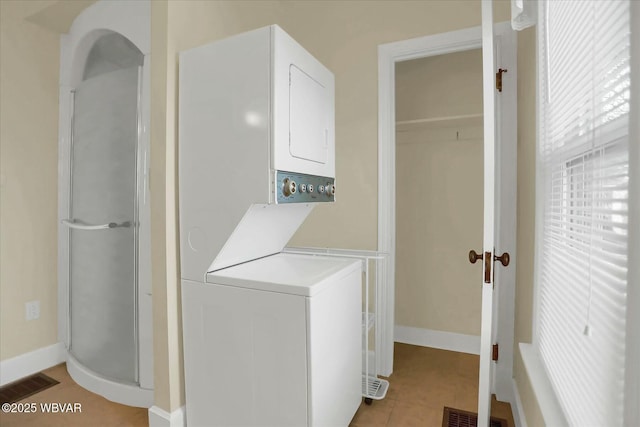 laundry area featuring light tile patterned floors, visible vents, laundry area, and stacked washing maching and dryer