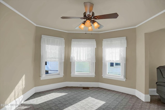 carpeted empty room with visible vents, ceiling fan, baseboards, and ornamental molding