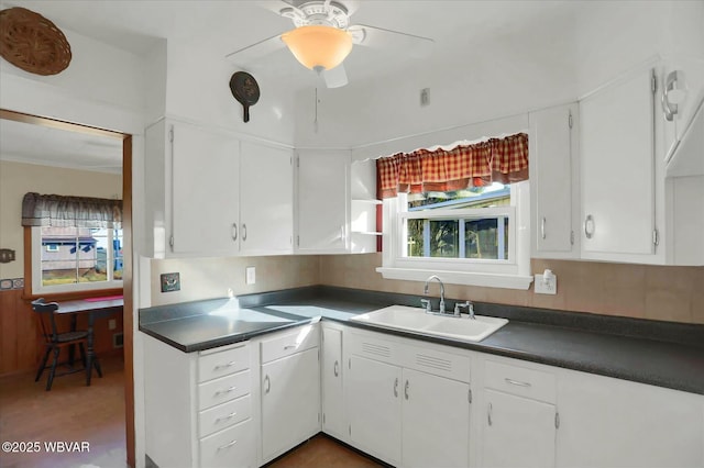 kitchen featuring dark countertops, white cabinetry, and a sink