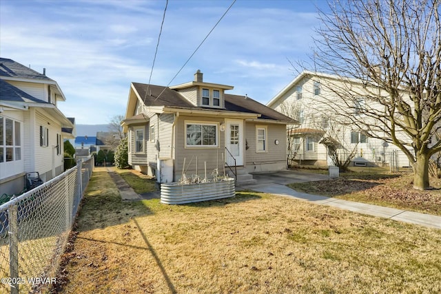 view of front of home with a front yard, entry steps, a chimney, and fence