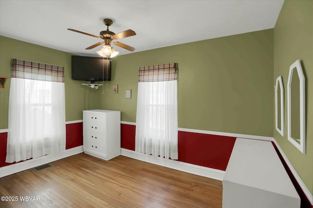 unfurnished bedroom with visible vents, ceiling fan, baseboards, and wood-type flooring