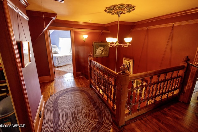 hallway with ornamental molding, hardwood / wood-style floors, and a notable chandelier