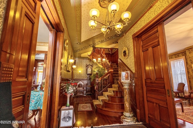 stairs featuring ornamental molding, hardwood / wood-style floors, and a chandelier