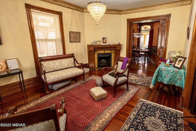 living area featuring a fireplace, dark wood-type flooring, ornamental molding, and a chandelier