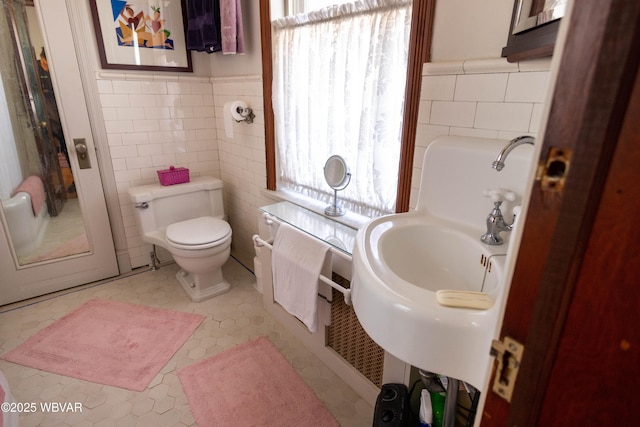 bathroom with toilet, tile patterned flooring, and tile walls