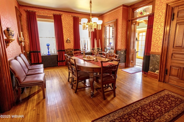 dining area with an inviting chandelier, radiator heating unit, and light wood-type flooring