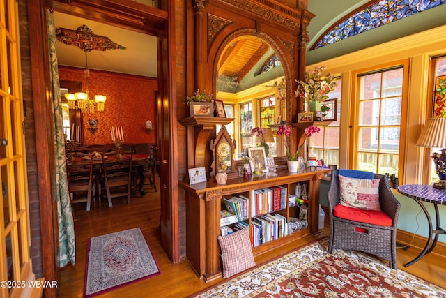 sitting room with hardwood / wood-style flooring, crown molding, vaulted ceiling, and a notable chandelier