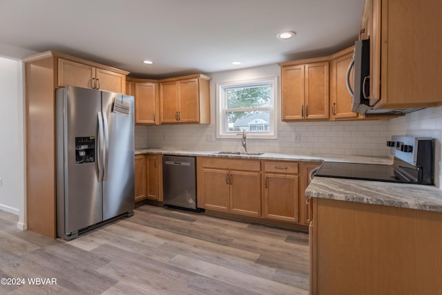 kitchen featuring sink, decorative backsplash, light wood-type flooring, appliances with stainless steel finishes, and light stone counters