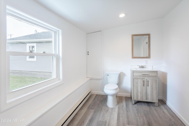 bathroom featuring a baseboard heating unit, wood-type flooring, lofted ceiling, toilet, and vanity