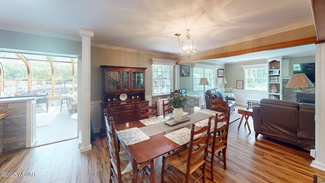 524 Pardee Rd, Millmont, PA 17845 - dining area featuring a fireplace, wood finished floors, a chandelier, ornamental molding, and decorative columns