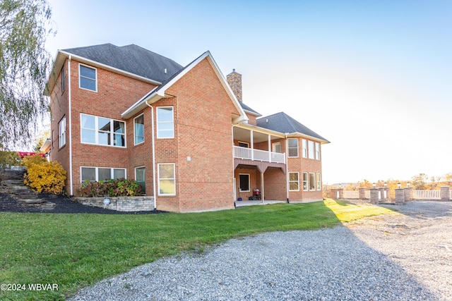 rear view of house with a yard and a balcony