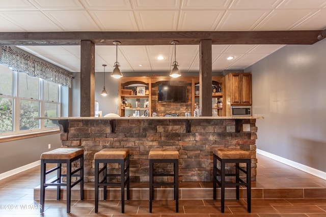 bar featuring stainless steel microwave and hanging light fixtures