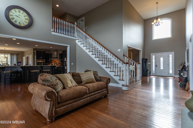 living room featuring dark wood-type flooring, a chandelier, and a high ceiling