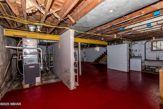 unfinished basement featuring stairs, a sink, and washer / dryer