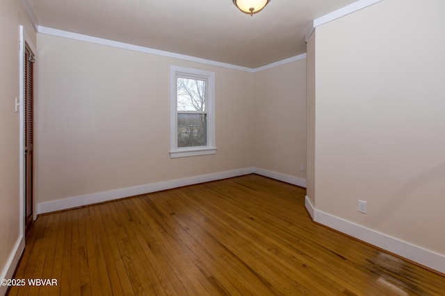 empty room featuring baseboards, light wood-style floors, and crown molding