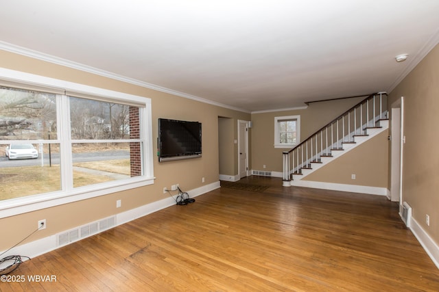 unfurnished living room featuring wood finished floors, visible vents, crown molding, and stairs