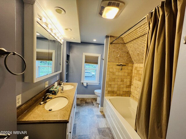 full bathroom with shower / bath combo, vanity, toilet, and a healthy amount of sunlight