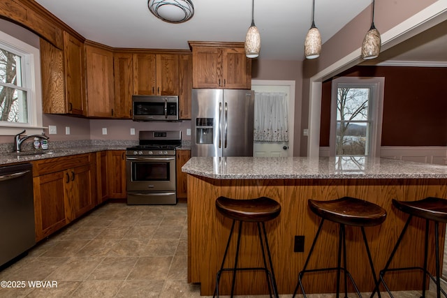 kitchen with appliances with stainless steel finishes, a breakfast bar, a sink, and light stone counters