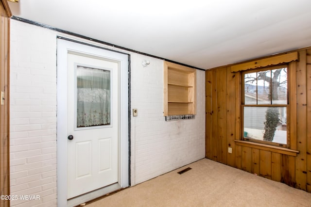 interior space featuring brick wall, visible vents, and light colored carpet