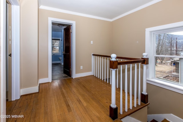 corridor featuring ornamental molding, baseboards, an upstairs landing, and wood finished floors