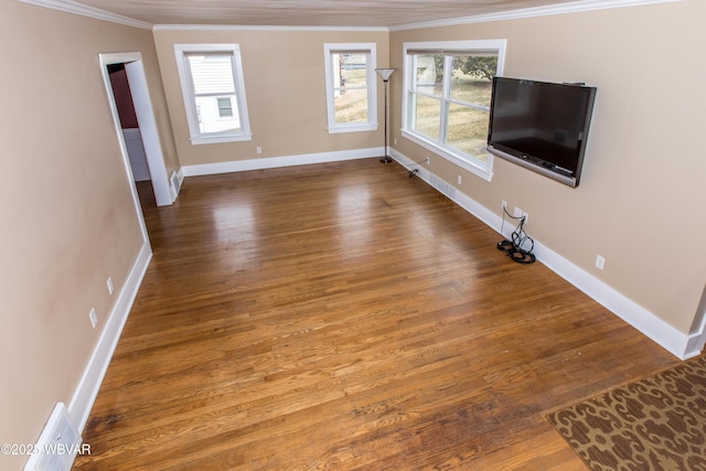 unfurnished living room with ornamental molding, a wealth of natural light, and wood finished floors