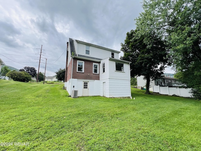 rear view of property featuring a lawn and central AC unit