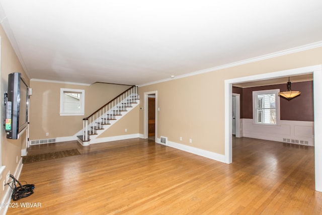 interior space with stairs, visible vents, wood finished floors, and ornamental molding