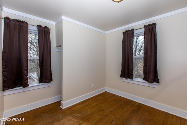 unfurnished room featuring crown molding, baseboards, and wood finished floors