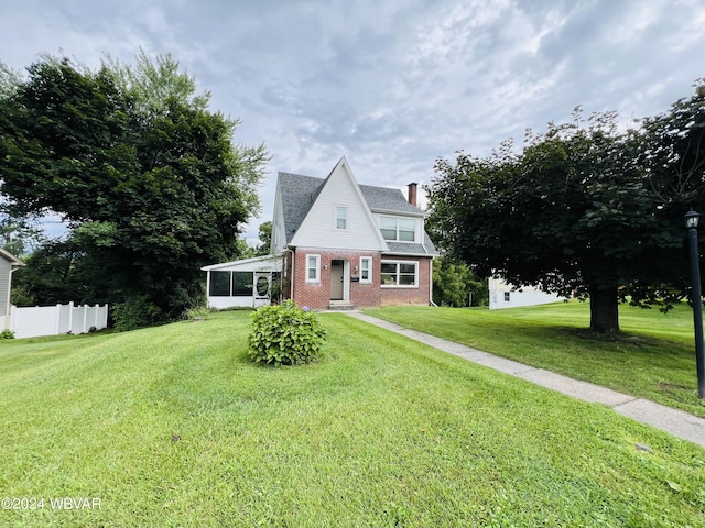 view of front of house with a front yard and a sunroom