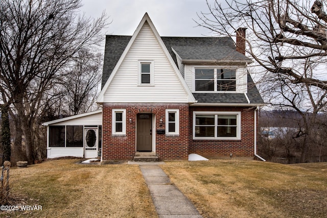 view of front of property featuring a front yard, brick siding, roof with shingles, and entry steps