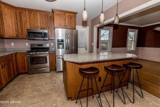 kitchen featuring stainless steel appliances, a kitchen bar, and light stone countertops