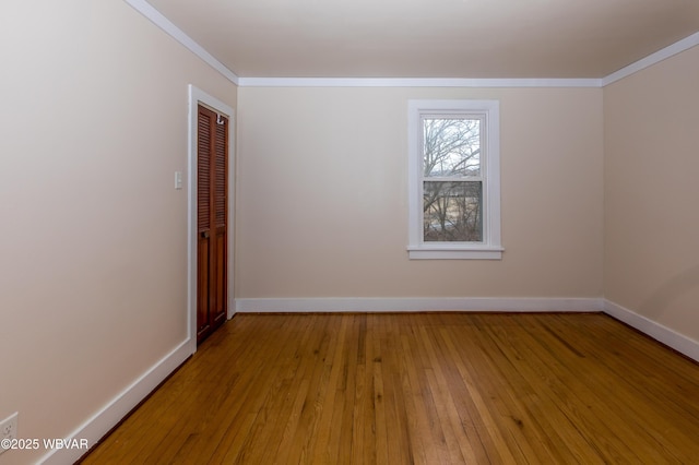 empty room with baseboards, ornamental molding, and wood finished floors