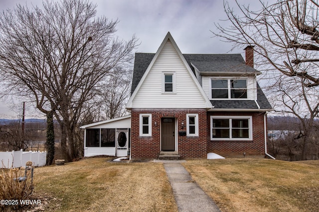 view of front of home with entry steps, brick siding, a front lawn, and roof with shingles