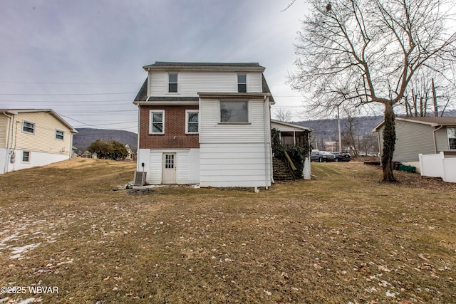 rear view of house with brick siding, a lawn, and central air condition unit