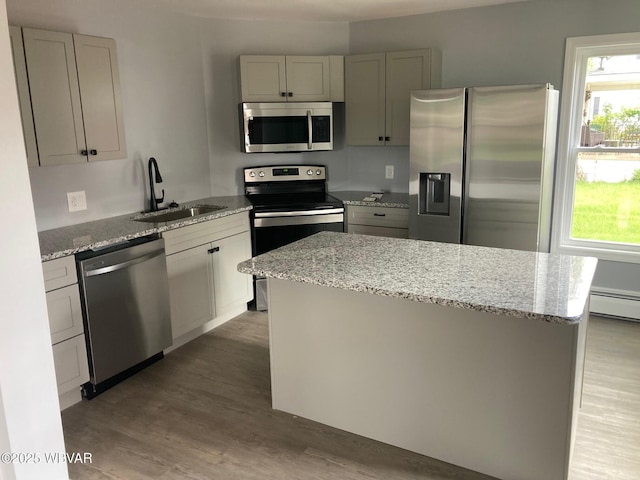 215 E 8th St, Watsontown, PA 17777 - kitchen featuring appliances with stainless steel finishes, a sink, wood finished floors, a kitchen island, and light stone counters